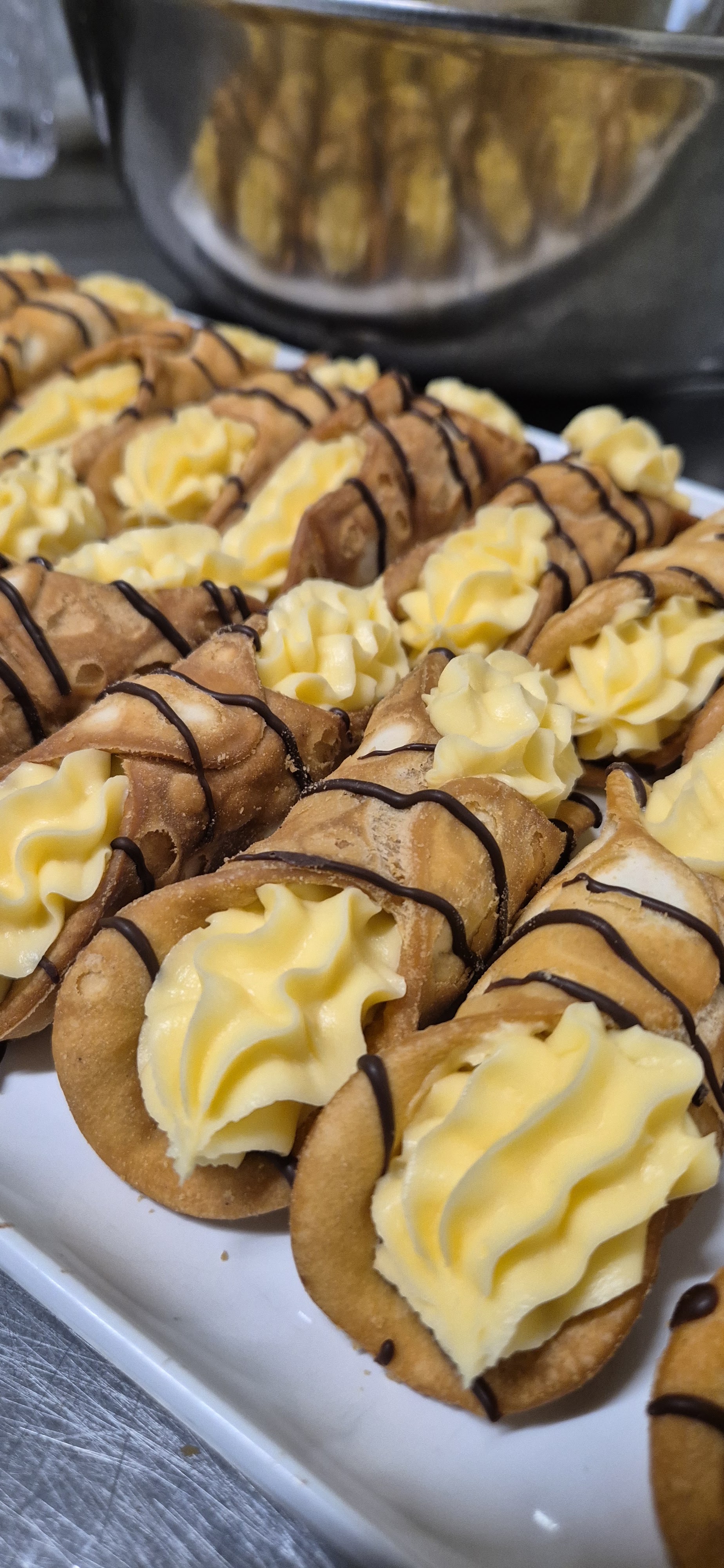 A tray of cannoli filled with cream and drizzled with chocolate