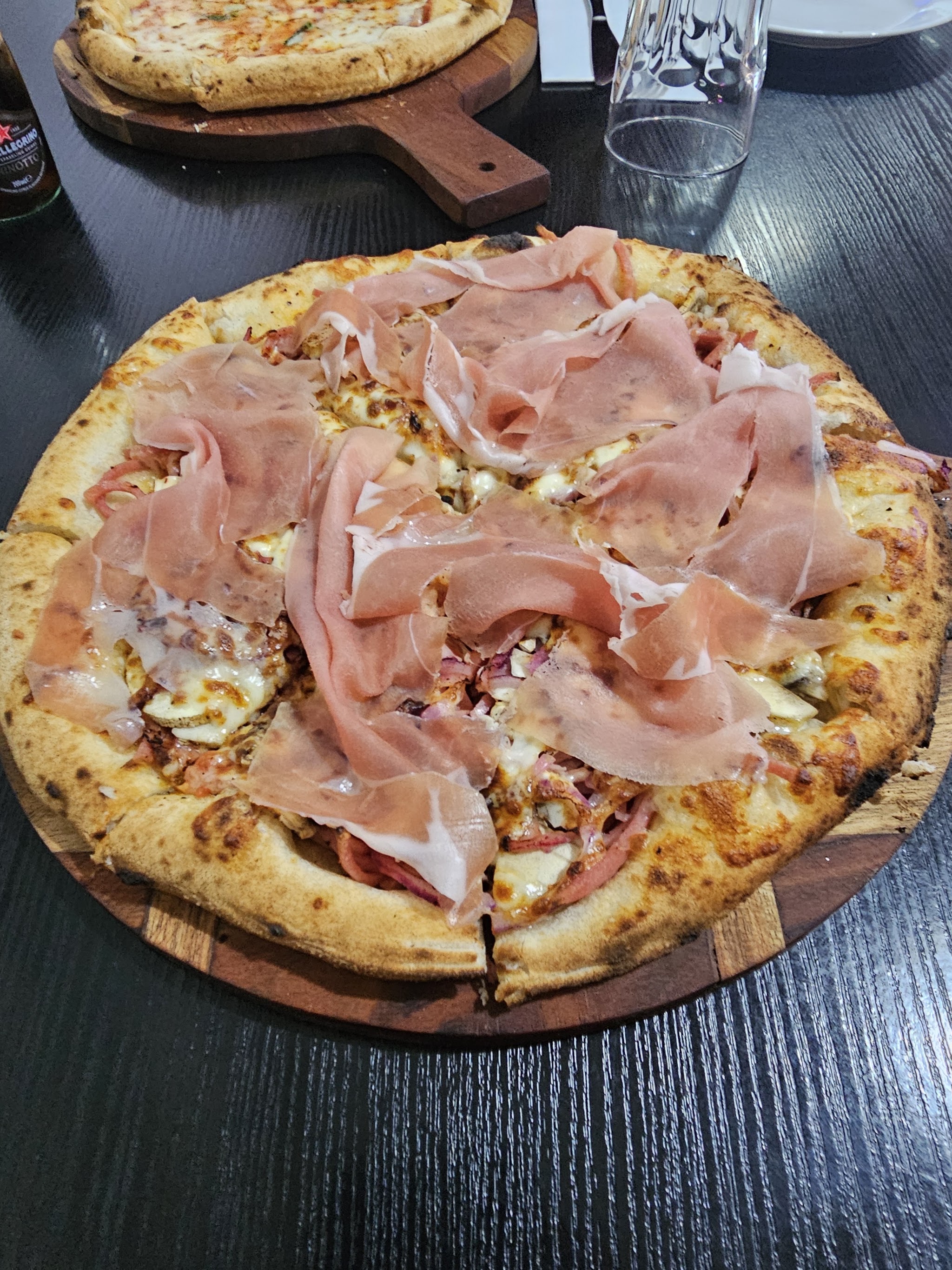 Wood-fired prosciutto pizza on a wooden board