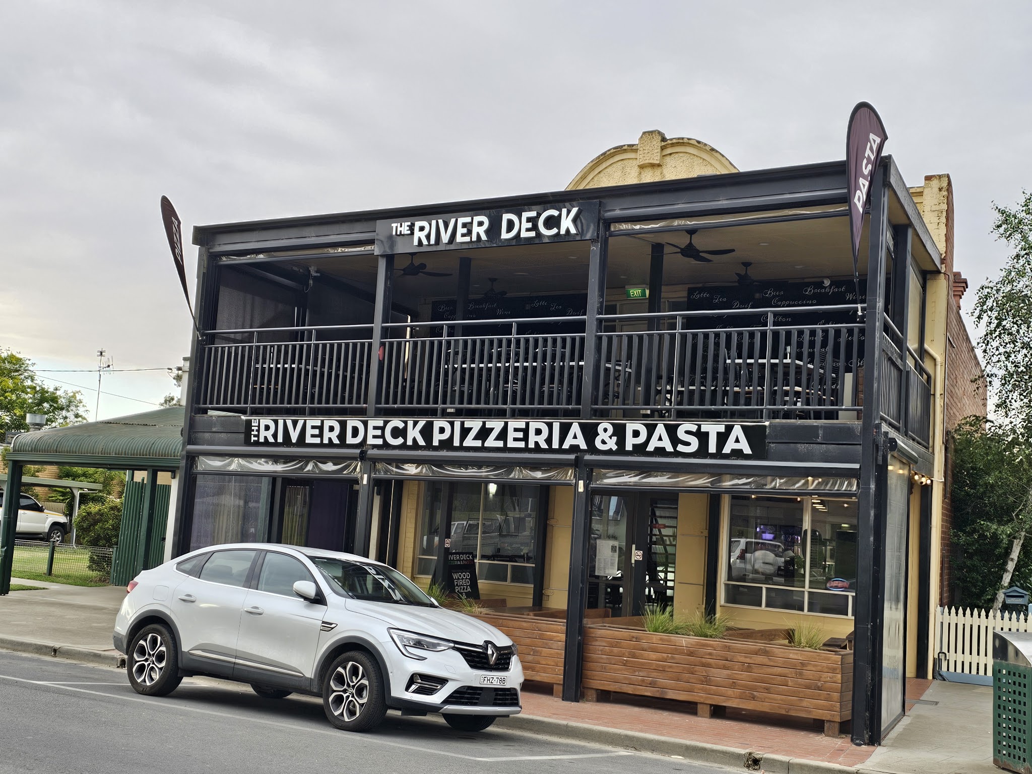 The two-storey River Deck building with its balcony and Pizza and Pasta flags